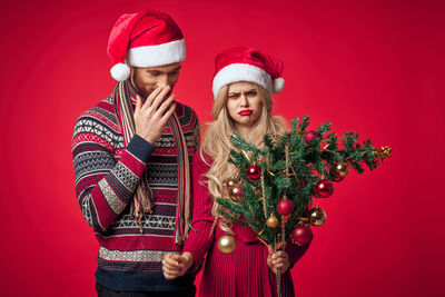 Full length of smiling woman in red christmas tree during winter