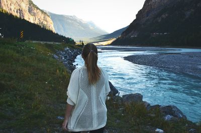 Rear view of woman standing by lake