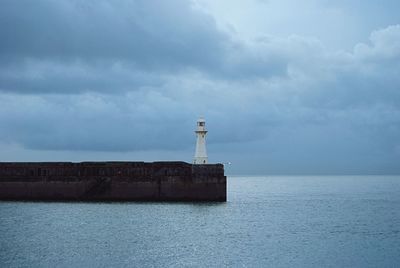 Lighthouse at sea against sky
