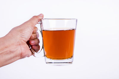 Close-up of hand holding drink against white background