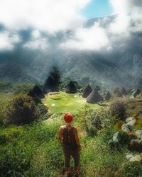 Rear view of woman walking on field against sky