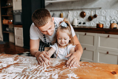 Funny happy dad and daughter baby cook together fool around and play with flour in  kitchen at home