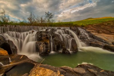 Scenic view of waterfall against sky