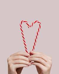 Cropped hand of woman holding heart shape against white background