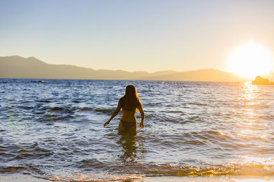 Mountain lake teen swims at sunset or sunrise for travel and adventure