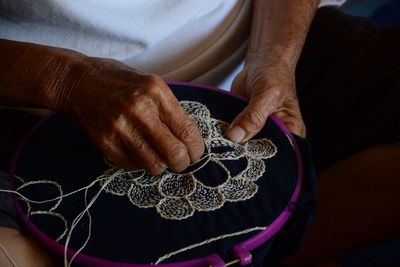 Midsection of senior man sewing design on textile