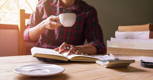 Soft focus, blur.close-up asian man in scottish shirt holding coffee drinking and read a book.