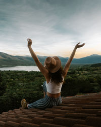 Rear view of woman with arms raised against sky