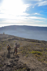 Rear view of people walking on mountain against sky
