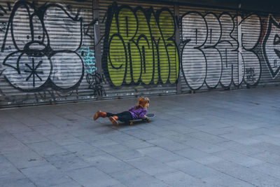 Full length of girl skateboarding while lying over footpath