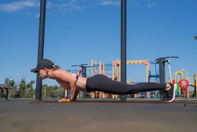 Happy woman in sportclothes working out in the sports ground in sunny summer day, training