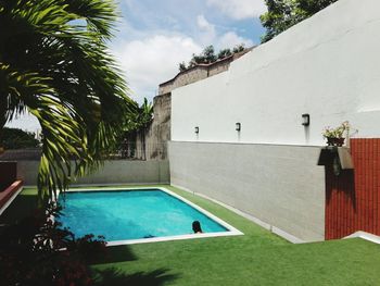 Swimming pool by trees against sky