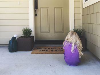 Rear view of girl sitting outside house