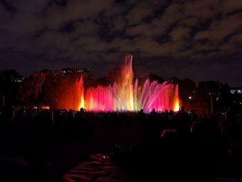 Illuminated fountain splashing water in city at night