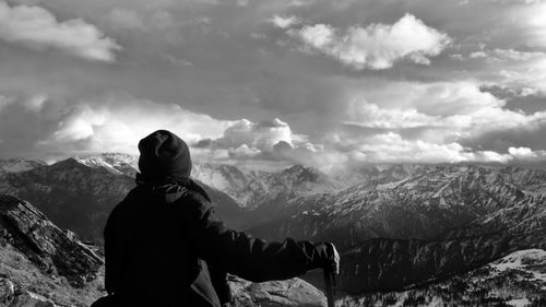 Rear view of man looking at snowcapped mountain against sky