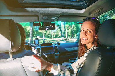 Portrait of smiling young woman sitting with friend in car