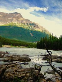Scenic view of river by mountains against sky