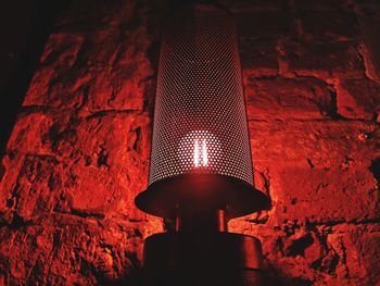 Low angle view of illuminated lamp against brick wall