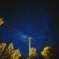 Low angle view of electricity pylon against star field