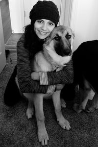 Portrait of woman with dog sitting at home