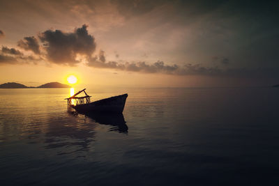 Silhouette boat in sea against sky during sunset