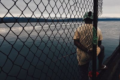 Woman seen through chainlink fence