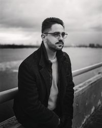 Man's portrait in black and white on city bridge looking ahead.