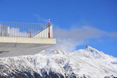 Low angle view of observation point and snowcapped mountains against sky