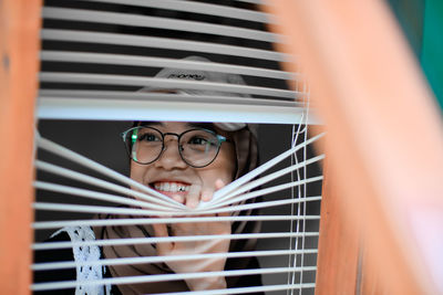 Low angle view of young woman looking through window