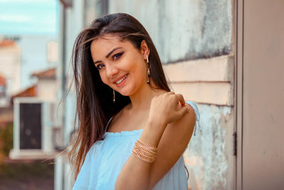 Portrait of smiling young woman against wall