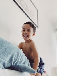 Portrait of happy boy on bed at home