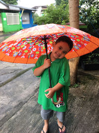 Full length portrait of cute boy holding umbrella during rainy season