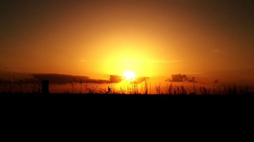 Scenic view of silhouette field against orange sky