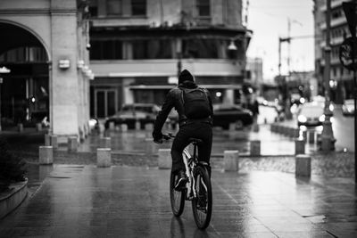 Rear view of man riding bicycle on street