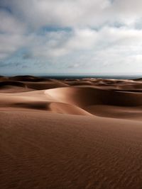 Scenic view of desert against cloudy sky