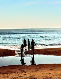 People on beach against clear sky