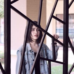 Portrait of beautiful young woman seen through metal pattern