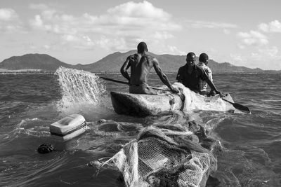 People on boat in sea against sky