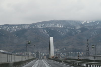 Road leading towards city against sky