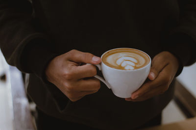 Close-up of hand holding coffee cup