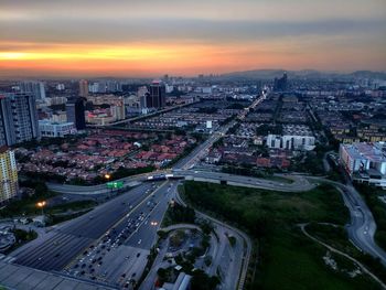 High angle view of street amidst buildings in city at sunset