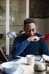 Tired teenage boy yawning while doing homework at home