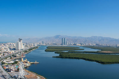 Aerial view of buildings in city against blue sky