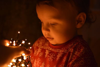Close-up of boy with illuminated string lights