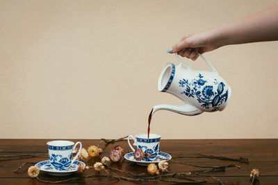 Midsection of hand holding ice cream on table