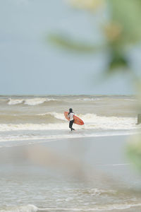 Man surfing in sea against sky