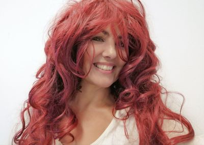 Close-up of smiling beautiful woman with redhead against white background