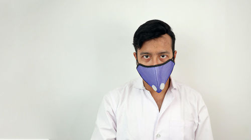 Portrait of young man standing against white background