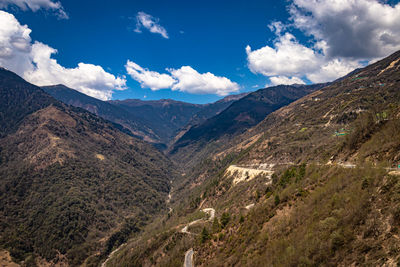 Mountain valley with curvy road and bright blue sky at sunny day from top