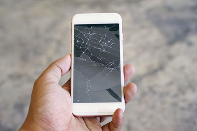 Close-up of hand holding crack smart phone